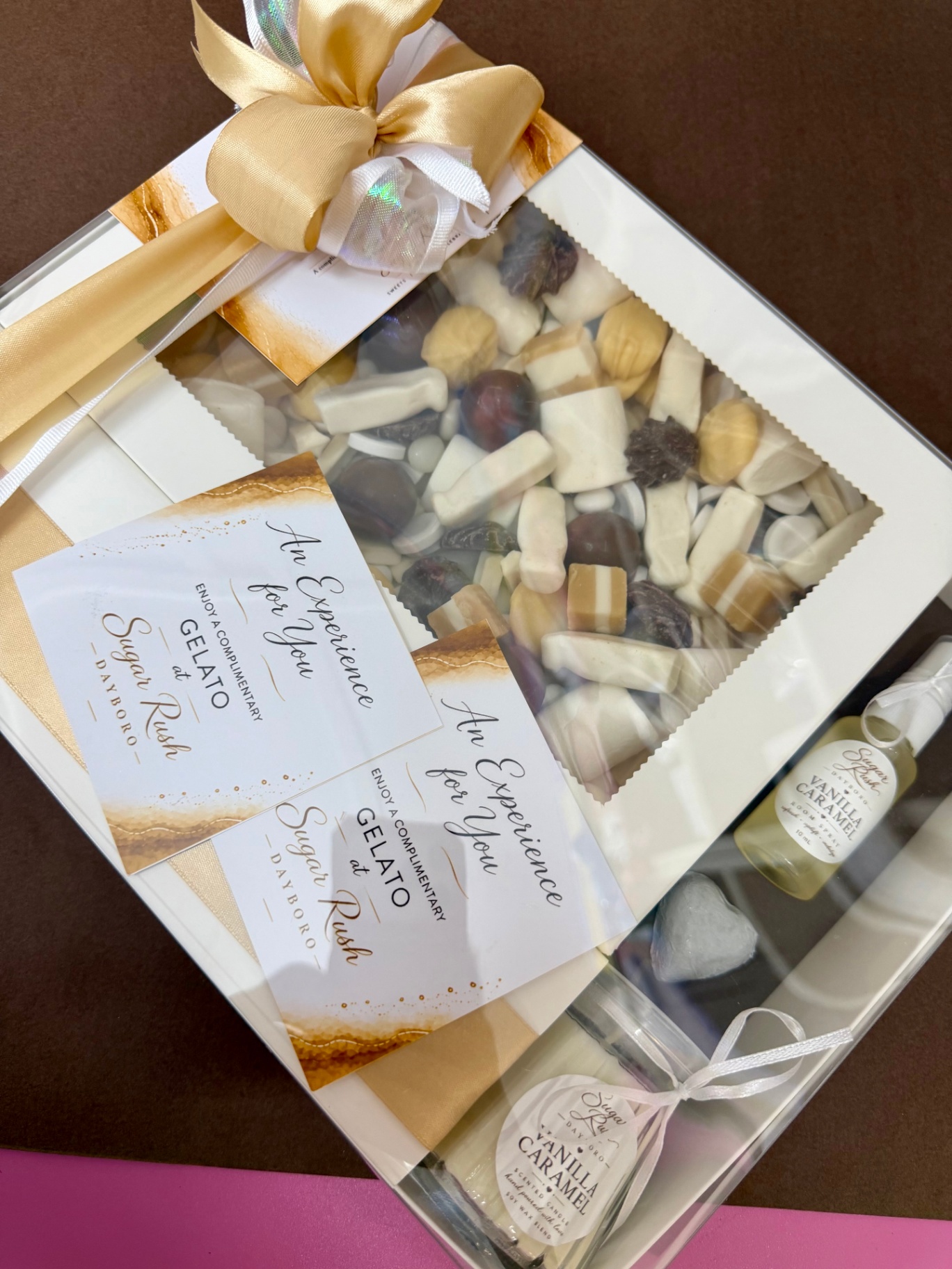 Luxury gold and cream gift box with assorted nougat, fudge and chocolates, vanilla caramel candle and room spray, finished with a gold satin bow