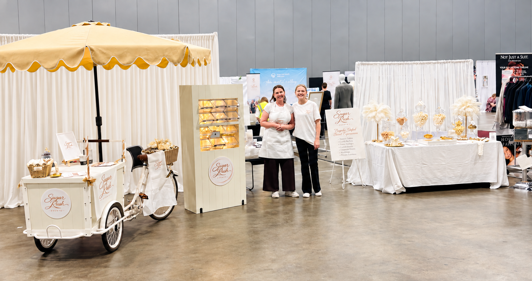 The Sugar Rush Events stall at Brisbane's Annual Wedding Expo — gelato trike, lit lolly wall and styled dessert table with the team
