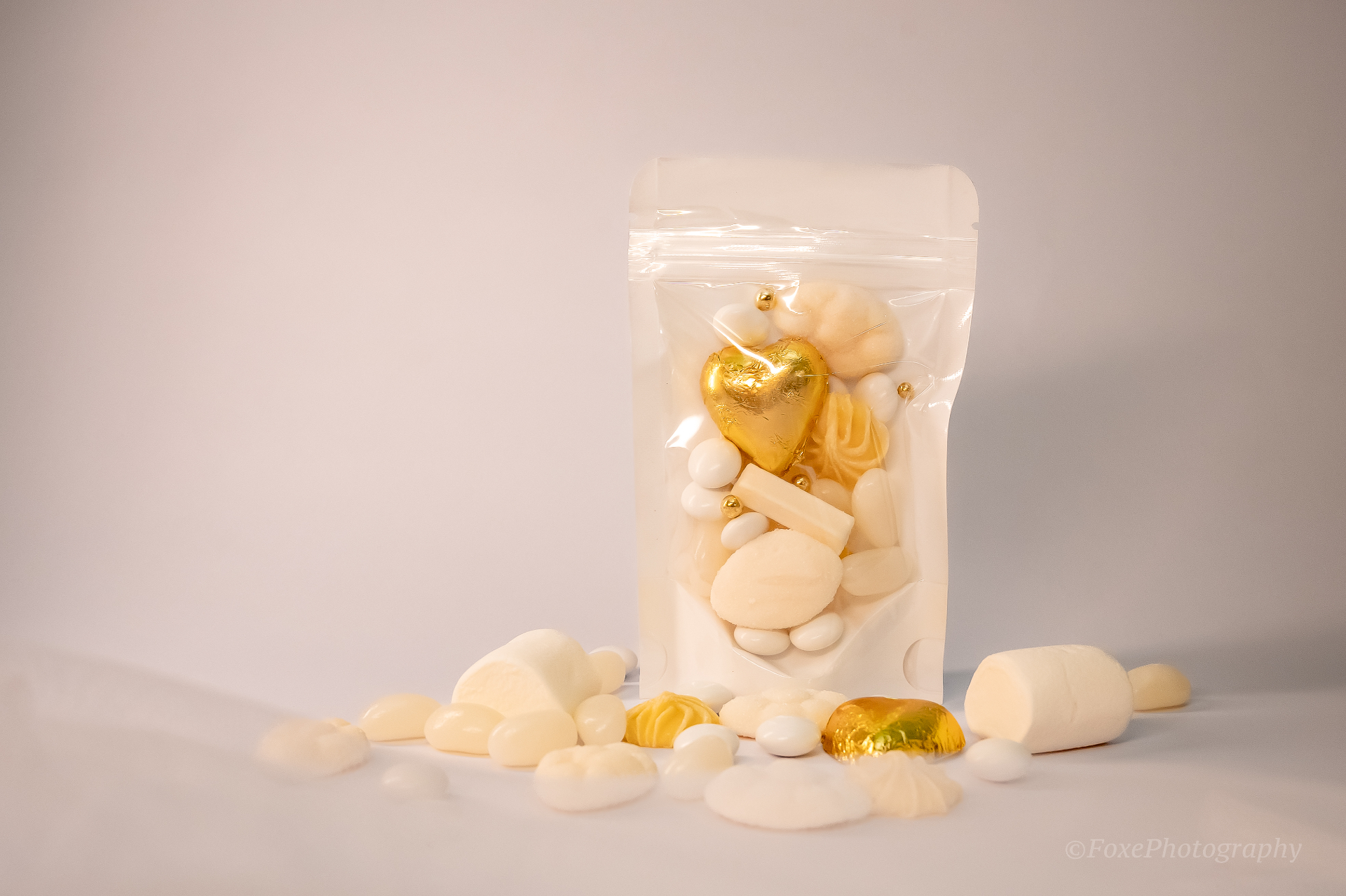 Elegant white and gold party favour bag with foiled gold heart chocolate, cream marshmallows and Jordan almonds